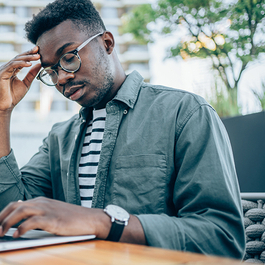 Stressed businessman using laptop at sidewalk cafe