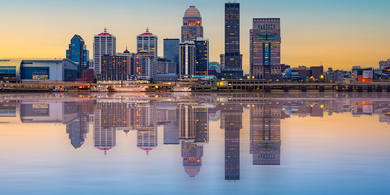 Beautiful sunset night view of Louisville Kentucky Skyline with river and lit buildings.