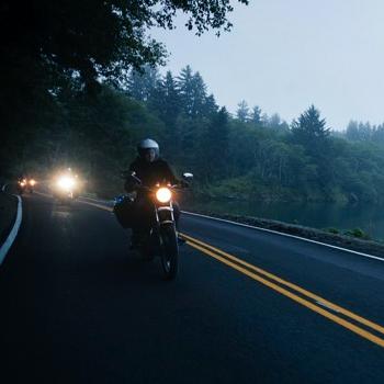 Motorcylce riders riding down a country road.