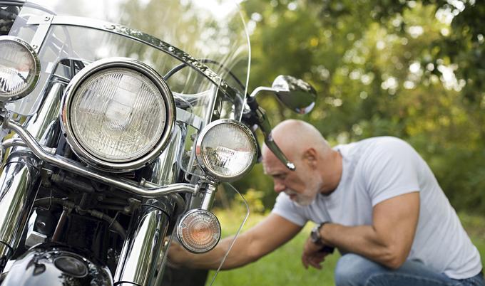 Man repairing motorcycle outdoors. 