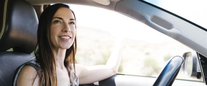 Woman sitting in driver seat of car smiling