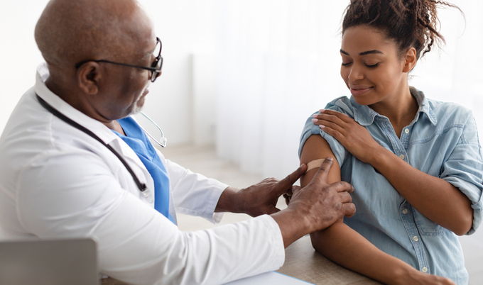 Doctor placing a bandaid on the arm of a patient.
