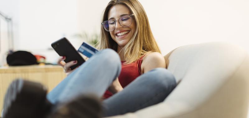 young woman making a payment on her cell phone with credit card 
