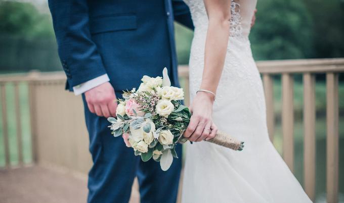 Bride holding flowers next to groom outdoors