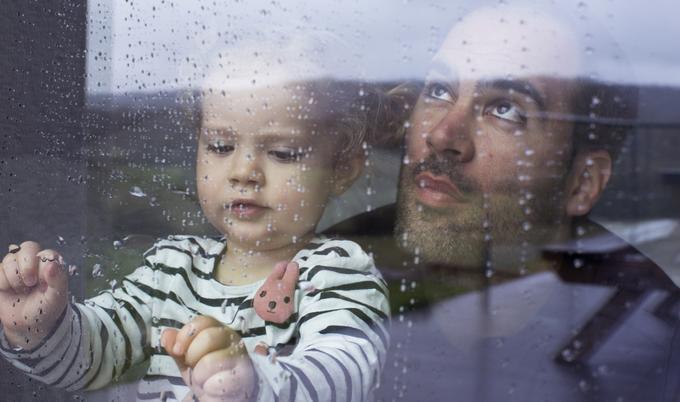 Man and little girl looking at raindrops through a window.