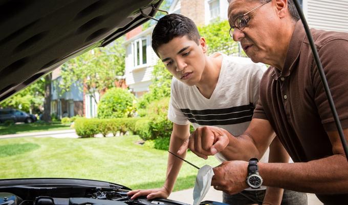 Father and son check car's oil.