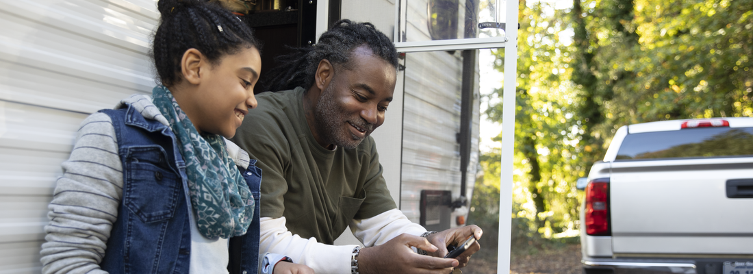 father and daughter sitting outside of RV
