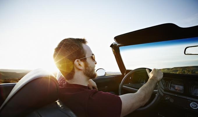 Man is driving a convertible car.