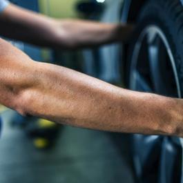 Mechanic using two hands grabbing a car tire.