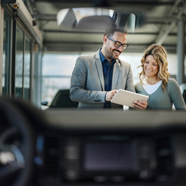 Happy salesman and his customer using touchpad in a showroom.
