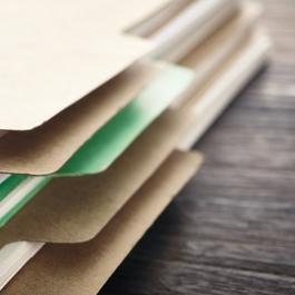 Stack of file folders on wooden desk.