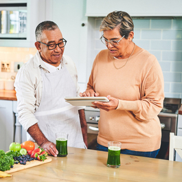 Husband and wife looking at tablet in the kitchen.