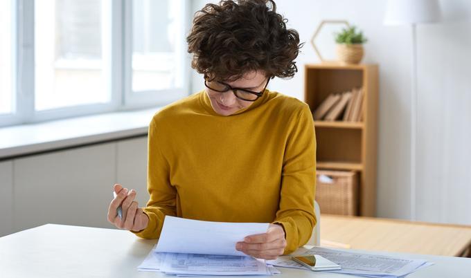 woman in yellow turtleneck reviewing documents.