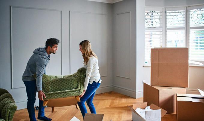 Young couple unloading cardboard boxes out of a van.