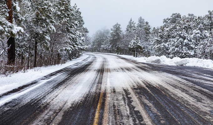 Dangerous country road covered in black ice and snow during winter