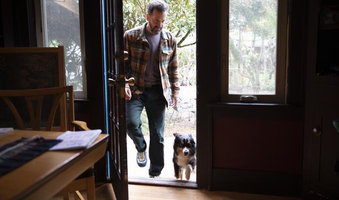 man with dog entering home