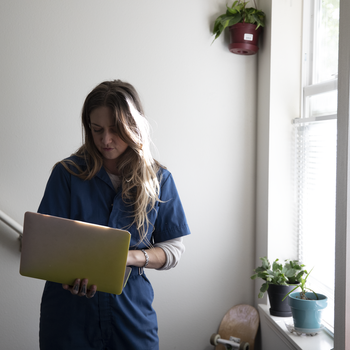 female looking at her computer while walking in home