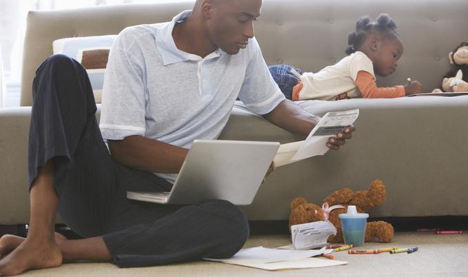 Man looking at paperwork while little girl colors.