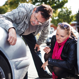 Man and woman examining car bumper