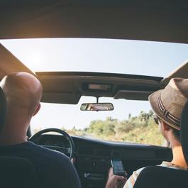 Two friends driving with sunroof.