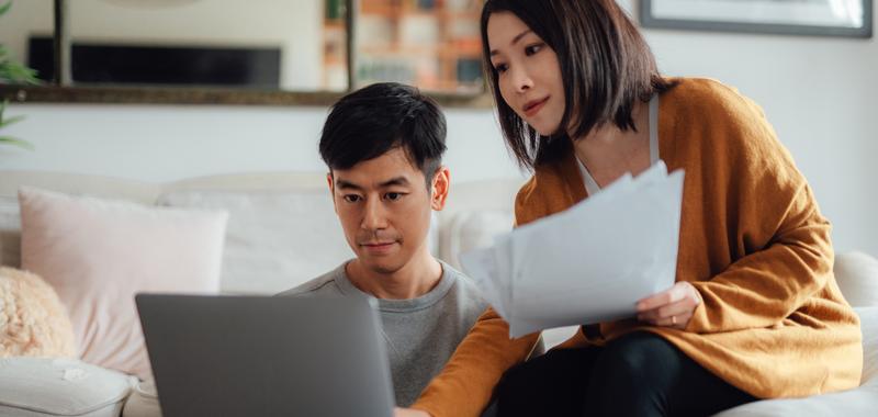 couple reviewing documents and laptop at home 