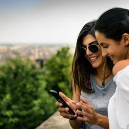 Two young women looking at something on a mobile phone together.