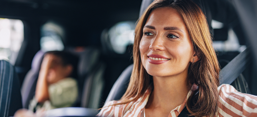 Mom Smiling While Driving Son to School in Morning.