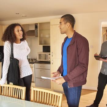 Couple standing with realtor in a kitchen.