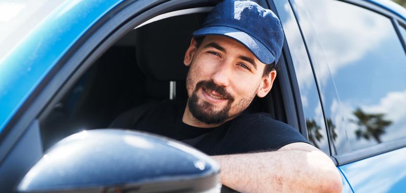 man leaning out of driver window smiling 
