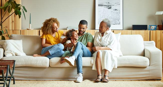 A family talking while sitting on a couch in the living room.