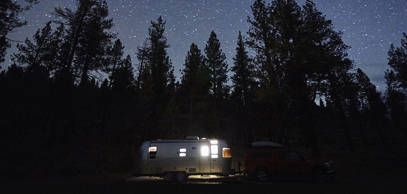 Camping trailer and silhouetted trees at night