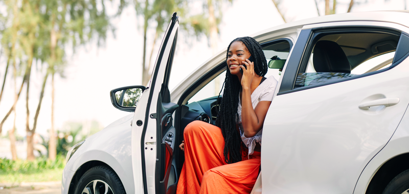 a woman on the phone sitting with the car door open