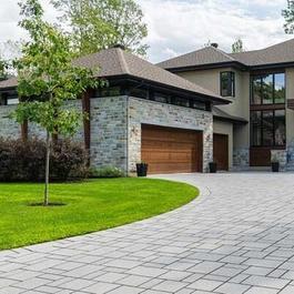 Residential home with paved driveway and beige brick exterior.