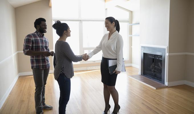 Young couple shaking hands with property manager. 