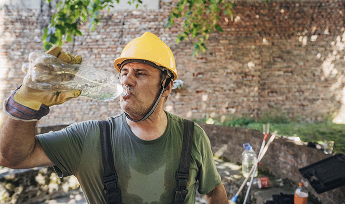 Worker stopping to drink a bottle of water.