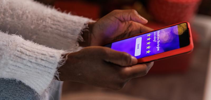 woman holding phone looking at reviews of a company 